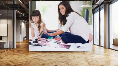 Mom, girl child and makeup on bed with brush, smile and helping hand for beauty in family home. Cosmetics, mother and daughter with foundation, palette and happy for learning with bonding in house Wall mural