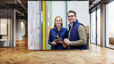 People, portrait and business checklist in warehouse with bulletin board for schedule or calendar for order details. Man, woman and clipboard for supplier information or notes, happy and together Wall mural