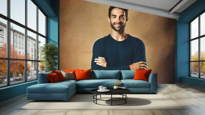 Portrait, man and fashion in studio for confidence for modeling, designer brand and hipster style. Handsome face, smile and model by brown background for winter clothes, cool hair and casting agency Wall mural