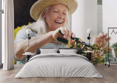 Senior, woman and trimming of plants in garden, home and smile for nature, outdoor and summer to relax. House, ecology and elderly person with hobby, happiness and hat for sun, retirement and weekend Wall mural