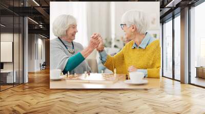 Senior woman, friends and high five for chess match, game or winning on table together at home. Happy elderly women in celebration, playing strategic board game for victory or checkmate in retirement Wall mural