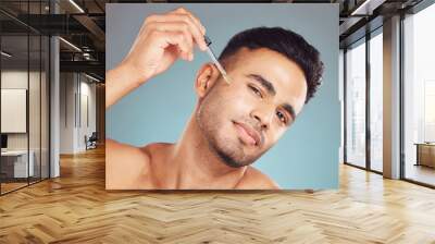 Skincare, portrait and man with serum in pipette, facial treatment product or skin glow on blue background. Cosmetics, retinol and male person with oil, hyaluronic acid or collagen solution in studio Wall mural