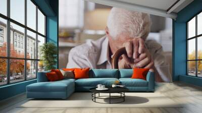 Sofa, cane and sad senior man with depression, grief or loss in living room of nursing home. Mental health, retirement and lonely person with disability, walking stick and thinking on couch in house Wall mural