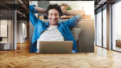 Stretching, relax and happy man on laptop in home living room, wellness or smile with reading email online. Peace of mind, computer or person on sofa for calm, zen or freelancer on social media break Wall mural