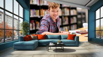 Student, portrait and notebook in library for study, education and university quiz with pen on table. Man, happy and books on school campus for college exam, research and learning with scholarship Wall mural