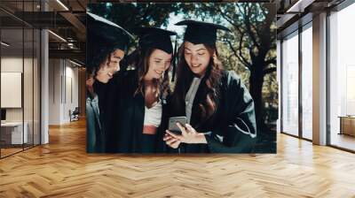 Students, phone and achievement for graduation outdoor with social media, academic success and reading text. Women, outside and graduate together with mobile for university, online chat and education Wall mural