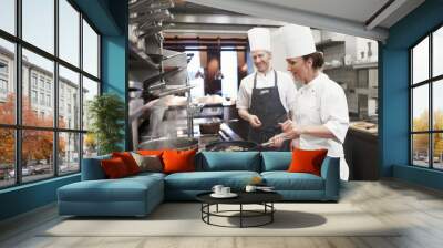 Teamwork, meat and chef with frying pan in kitchen for catering service, fine dining or prepare dish. Hospitality, presentation and people for cooking meal, food industry or dinner in restaurant Wall mural