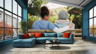 Volunteer, senior woman and hug on bench outdoor for nursing support, retirement and comic conversation. Back, caregiver and people with embrace for wellness assistance, empathy and residential care Wall mural