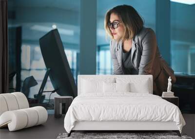 Woman, employee and reading on computer in office on browsing internet, online and research for ideas. Female person, workplace and desk with deadline or overtime, project and standing as hr Wall mural