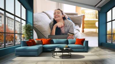 Woman, home and laughing on tablet with debit card on sofa for online shopping, payment and saving plan. Rewards, living room and happy on couch for internet banking, budget and investment or finance Wall mural