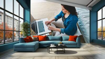 Woman, laptop and above or working in home, freelancer and checking email for job in living room on sofa. Remote, online research and social media with notebook, planner and apartment or lounge Wall mural