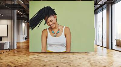 Woman, laughing and dreadlocks in studio for fashion, stylish clothes and cool look with confidence. Female person, jewelry and trendy accessory by mockup with hair shake, energy and green background Wall mural