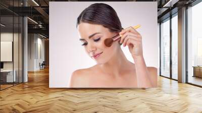 Woman, powder brush and apply makeup in studio, skincare and cosmetics tool for highlighter. Female person, facial treatment and white background for beauty, foundation transformation and blush Wall mural