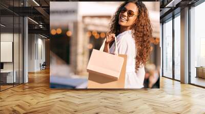 Woman, sunglasses and shopping bag in city or gift discount or retail sale, product or promotion. Female person, travel and happy in California with buying purchase or fashion deal, urban or customer Wall mural