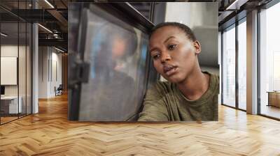 Woman, travel and depressed by window in train with bad memory, sad and lonely on public transport. African girl, person and tired with anxiety, lost or stress for future in subway on railway journey Wall mural