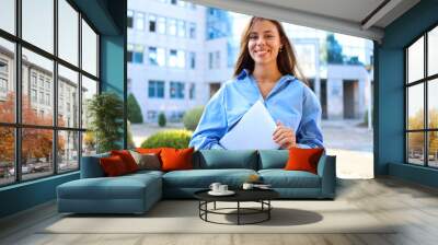 Joyful young professional stands on the street with a warm smile Wall mural