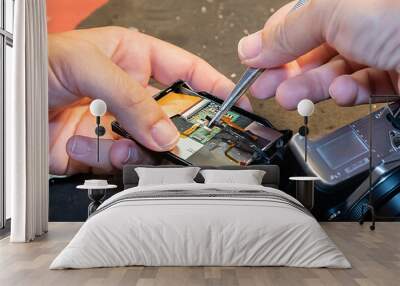 Shot of a Hispanic man's hands adjusting a camera circuit board with tweezers. Wall mural