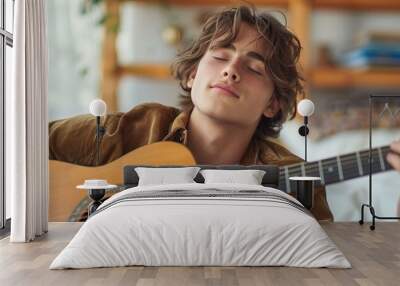 A teenager practicing guitar with passion, eyes closed and lost in music against a white bedroom wall. Wall mural