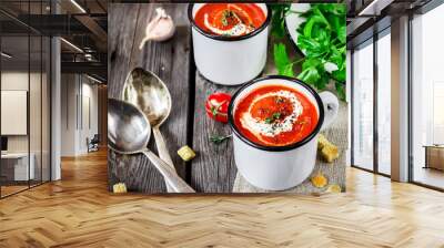 Tomato cream soup in mugs and greens on a wooden table. Wall mural