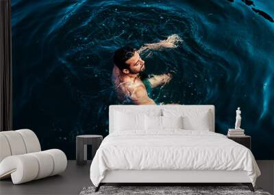 Relaxed man floating in dark water Wall mural