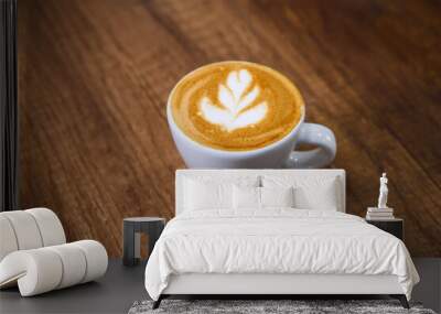 White cup of cappuccino standing on wooden table with latte art Wall mural