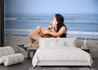 Young woman is relaxing on the beach with her xoloitzcuintli dog Wall mural