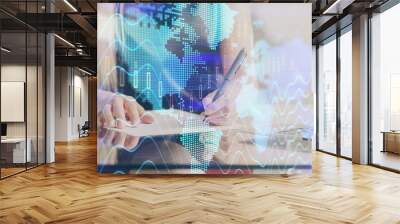 A woman hands writing information about stock market in notepad. Forex chart holograms in front. Concept of research. Wall mural