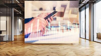 Double exposure of man's hands holding and using a phone and financial graph drawing. Analysis concept. Wall mural