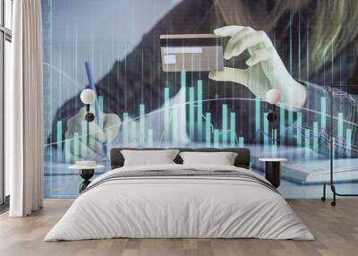 Double exposure of woman on-line shopping holding a credit card and financial graph drawing. Stock market E-commerce concept. Wall mural