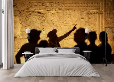 Group of unrecognizable tourist archeologists standing in silhouette in front of ancient Egyptian hieroglyphs Wall mural