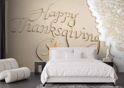 Happy Thanksgiving message handwritten on smooth sand beach with decorative starfish and oncoming wave Wall mural