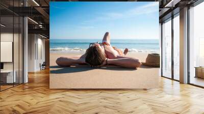 Sunbathing man relaxing on the smooth sand of an empty beach Wall mural