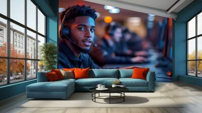 A young man wearing a headset looks confidently at the camera while gaming at a computer desk. Wall mural