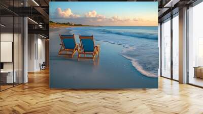 Two empty chairs on a sandy beach facing the ocean at sunrise with blue skies and white clouds. Wall mural