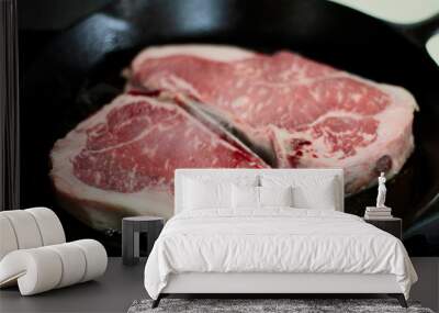 New York strip steaks cooking in a cast iron pan on a natural gas stove top.
 Wall mural