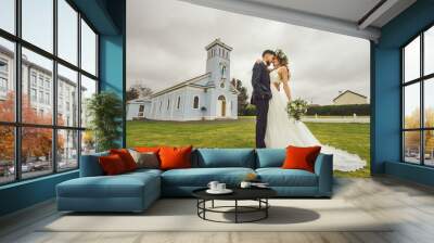 young couple bride groom getting married wedding posed photos at seaside sea beach hairpiece flowers bouquet church Wall mural