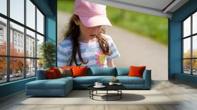 Adorable little girl outdoors on a sunny day wearing a pink cap Wall mural