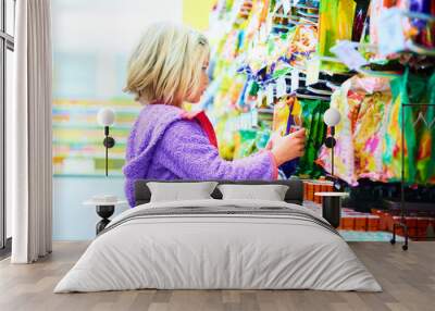 Adorable child blond girl select sweets on shelves in supermarket  Wall mural