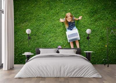 Child blond girl working on laptop. Playing games or watching movie. View from above
 Wall mural