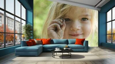 Four year old child blond girl holding a worm in the garden Wall mural