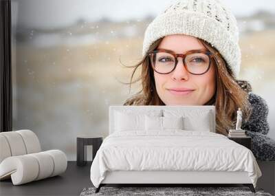 Beautiful young woman smiling while snowing outside Wall mural