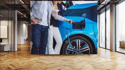 Couple charging their new electric car Wall mural