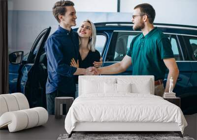 Couple choosing  a car in a car showroom and talking to the dealer Wall mural