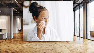 Girl cleaning her face using cotton pad Wall mural