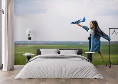 Little girl playing with toy plane in the field Wall mural