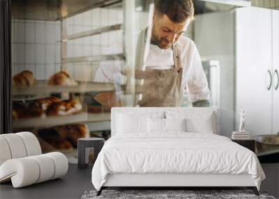 Man baker using flour to prepare dough for baking Wall mural