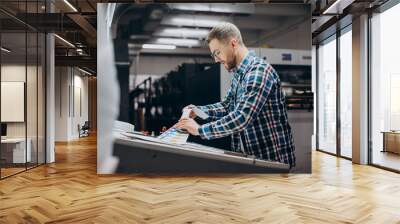 Man working in printing house with paper and paints Wall mural