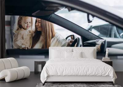 Mother with her little daughter choosing a car in a car showroom Wall mural