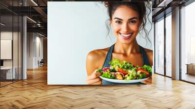 Smiling fit young woman holding a fresh salad plate Wall mural