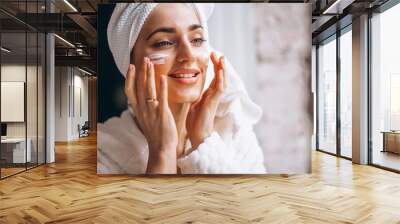 Woman applying moisturizing face cream Wall mural